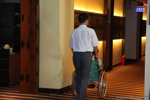 坐在轮椅上的小男孩由父亲推着前来参观十八子集团世界发烧音响博物馆